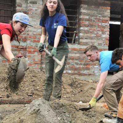 Volunteers from Projects Abroad dig up sand for cement during their building volunteer work in Nepal. Volunteers in Nepal dig up sand for cement to help rebuild schools as part of their construction volunteer project.